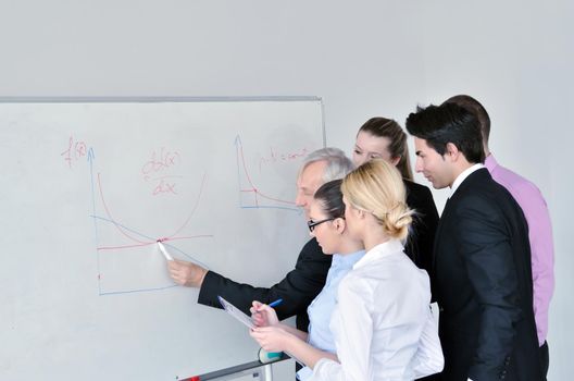 Senior male business man giving a presentation at a  meeting at modern light office on a table board