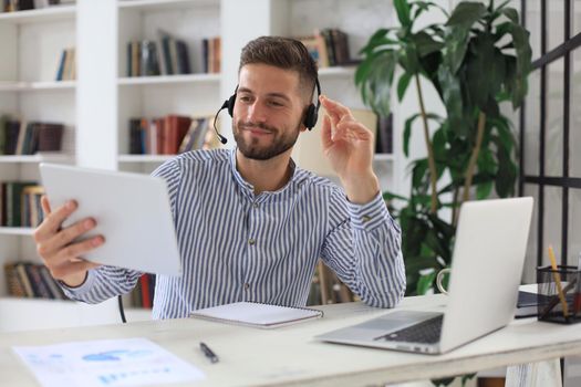 Confident man wearing headset speaking and watching business webinar training, listening to lecture