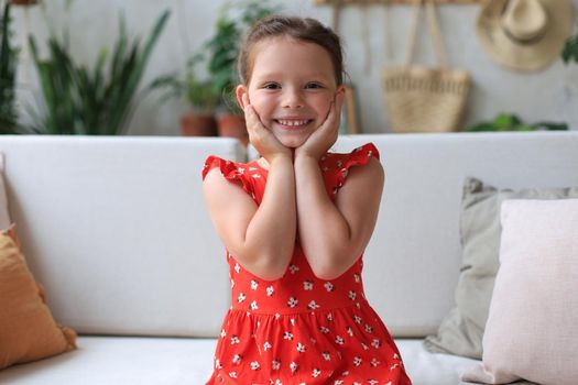 Excited child looking at camera while sitting in living room at home