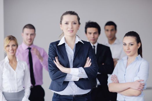 Successful business woman standing with her staff in background at modern bright office