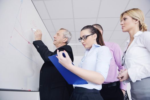 Senior male business man giving a presentation at a  meeting at modern light office on a table board