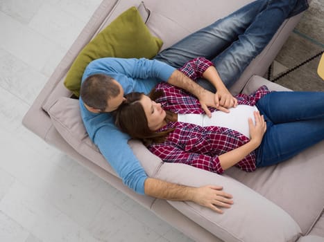 top view of happy pregnant couple relaxing on sofa couch at home