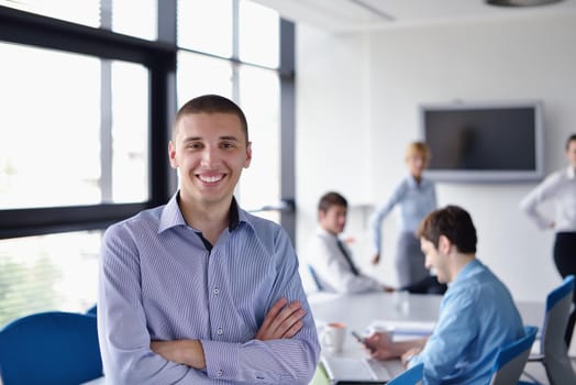 Portrait of a handsome young  business man  on a meeting in offce with colleagues in background