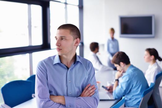 Portrait of a handsome young  business man  on a meeting in offce with colleagues in background