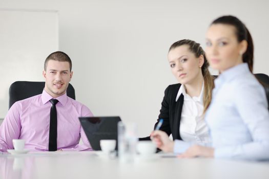 Group of young business people sitting in board room during meeting and discussing with paperwork