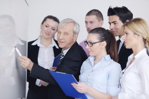 Senior male business man giving a presentation at a  meeting at modern light office on a table board