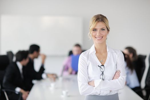 Successful business woman standing with her staff in background at modern bright office