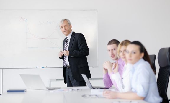 Senior male business man giving a presentation at a  meeting at modern light office on a table board