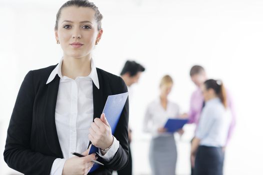 Successful business woman standing with her staff in background at modern bright office