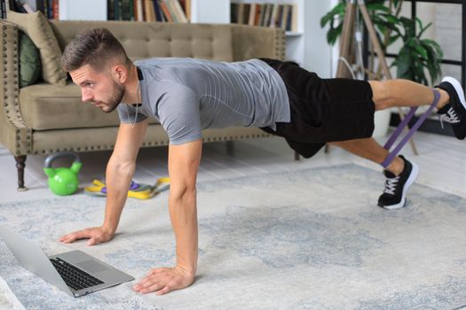 Attractive beared man doing plank exercise at home during quarantine. Fitness is the key to health