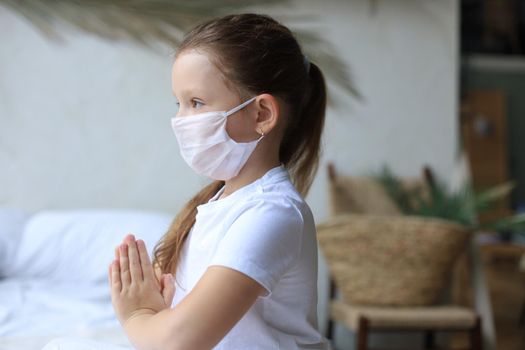 Little girl wearing mask for protect Covid-19. She praying in the morning for a new day freedom to world corona virus. Little girl hand praying for thank GOD.