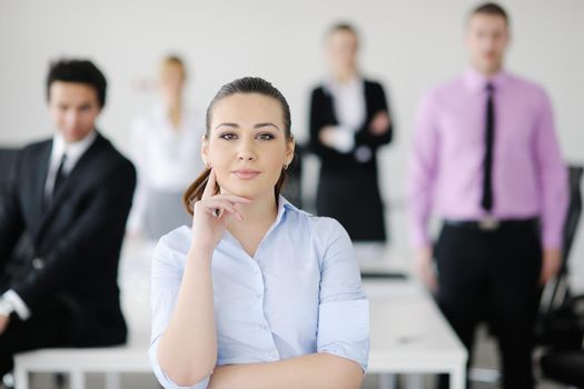 Successful business woman standing with her staff in background at modern bright office