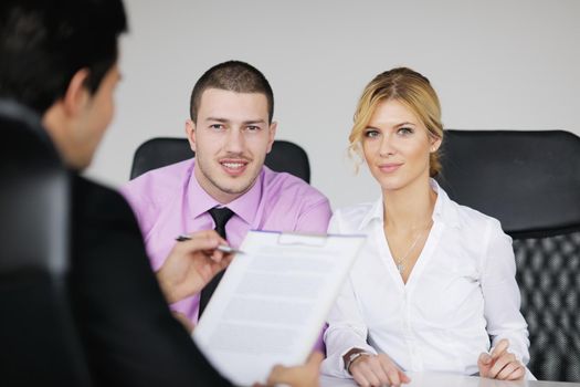 Group of young business people sitting in board room during meeting and discussing with paperwork