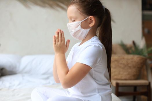 Little girl wearing mask for protect Covid-19. She praying in the morning for a new day freedom to world corona virus. Little girl hand praying for thank GOD.