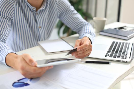 Young modern business man working using digital tablet while sitting in the office