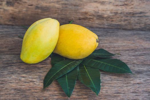 Mango and mango leaves on an old wooden background.