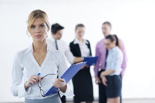 Successful business woman standing with her staff in background at modern bright office