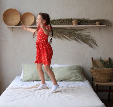 Happy little girl jumping on bed, singing a song