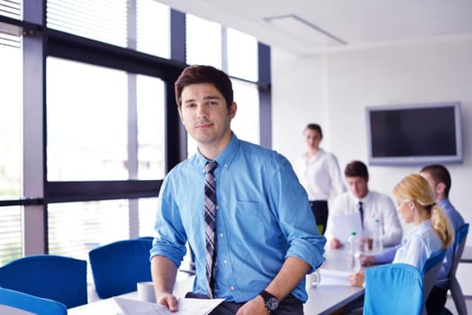 Portrait of a handsome young  business man  on a meeting in offce with colleagues in background