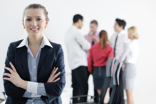 Successful business woman standing with her staff in background at modern bright office