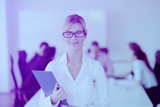 Successful business woman standing with her staff in background at modern bright office