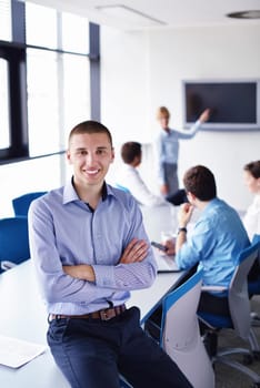 Portrait of a handsome young  business man  on a meeting in offce with colleagues in background