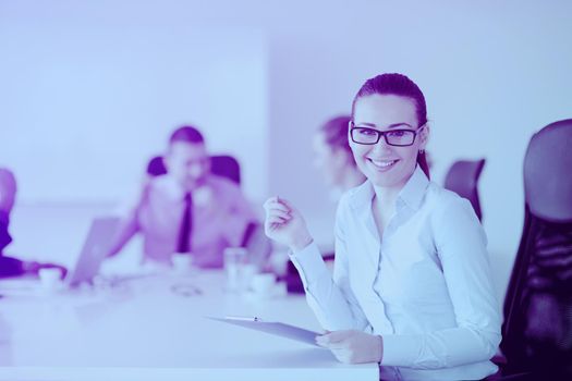 Successful business woman standing with her staff in background at modern bright office