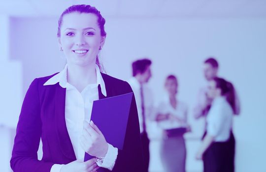 Successful business woman standing with her staff in background at modern bright office