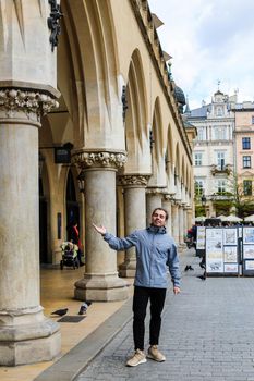 Young male tourist standing near columns on Main Square in Poland, Krakow. Concept of cheap traveling to Europe.