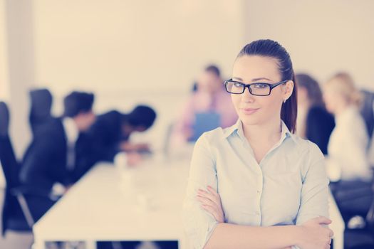 Successful business woman standing with her staff in background at modern bright office