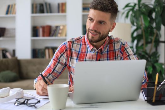 Happy young business man is analizing financial documents from home during self isolation