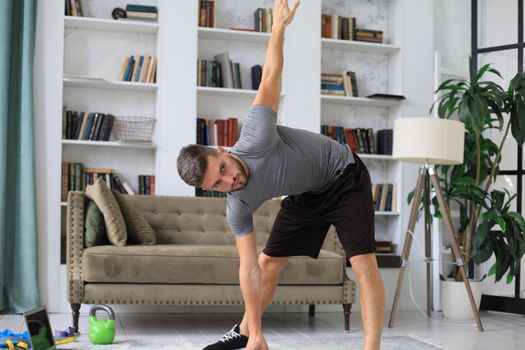 Handsome man doing sport exercise at home during quarantine. Concept of healthy life