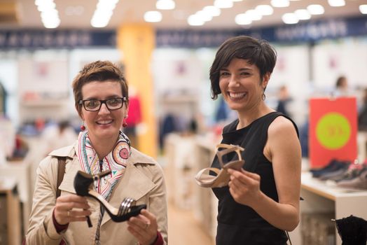 Two Girl-Friends On Shopping Walk On Shopping Centre With Bags And Choosing