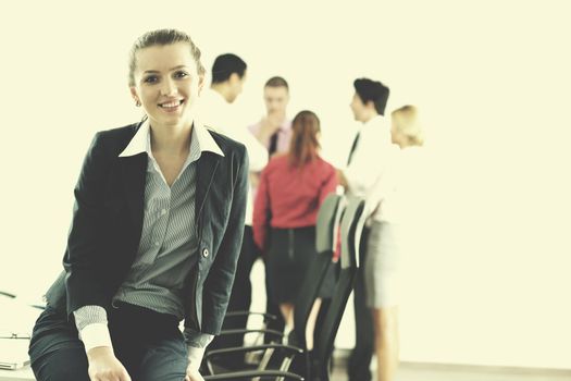 Successful business woman standing with her staff in background at modern bright office