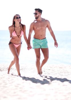 Guy and the girl walking along the beach. summer vacation on the coast.