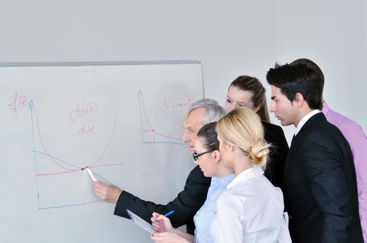 Senior male business man giving a presentation at a  meeting at modern light office on a table board