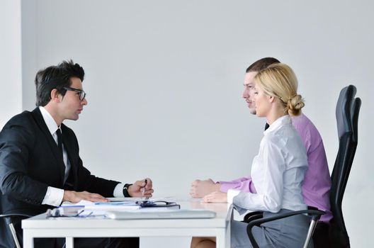 Group of young business people sitting in board room during meeting and discussing with paperwork