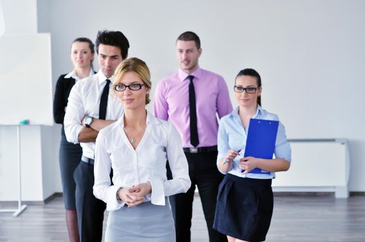 Successful business woman standing with her staff in background at modern bright office