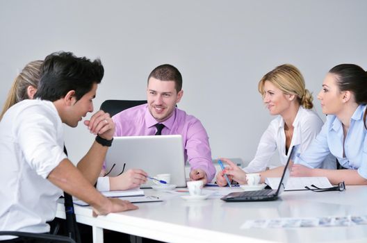 Group of young business people sitting in board room during meeting and discussing with paperwork