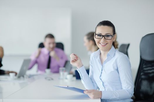 Successful business woman standing with her staff in background at modern bright office