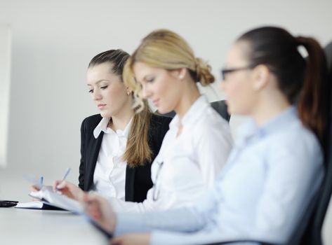 Successful business woman standing with her staff in background at modern bright office