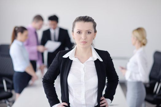 Successful business woman standing with her staff in background at modern bright office