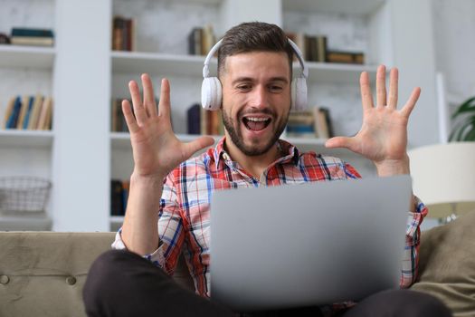 Smiling businessman greeting colleagues in video conference and negotiating distantly from home