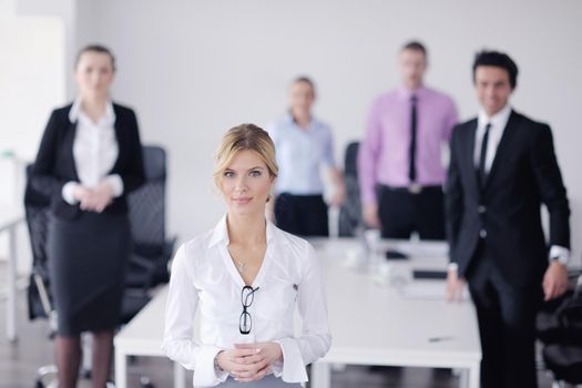 Successful business woman standing with her staff in background at modern bright office