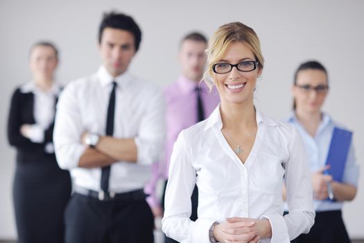 Successful business woman standing with her staff in background at modern bright office