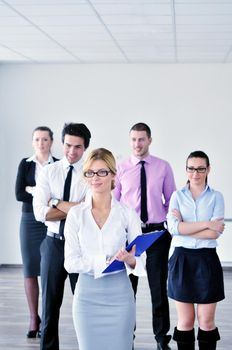 Successful business woman standing with her staff in background at modern bright office