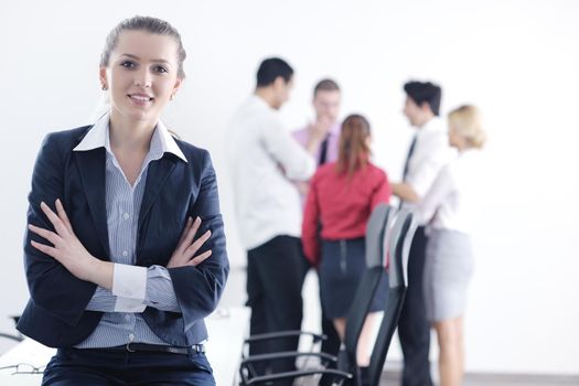 Successful business woman standing with her staff in background at modern bright office