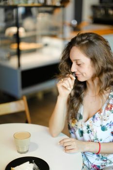 Young charming woman with cup of coffee sitting at cafe and resting. Concept of having kunch and resting at break.