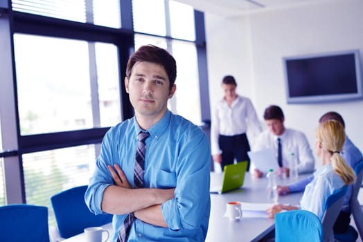 Portrait of a handsome young  business man  on a meeting in offce with colleagues in background