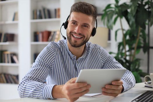 Confident man wearing headset speaking and watching business webinar training, listening to lecture